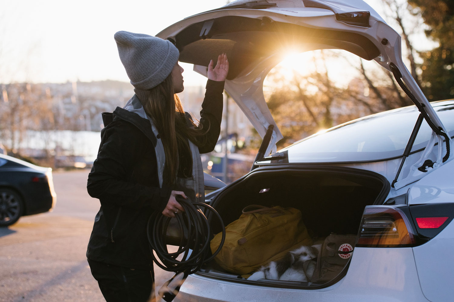 Kvinde med ladekabel ved bagagerummet bag en hvid elbil - nyhed om zaptec go ladeboks til prøvekunder